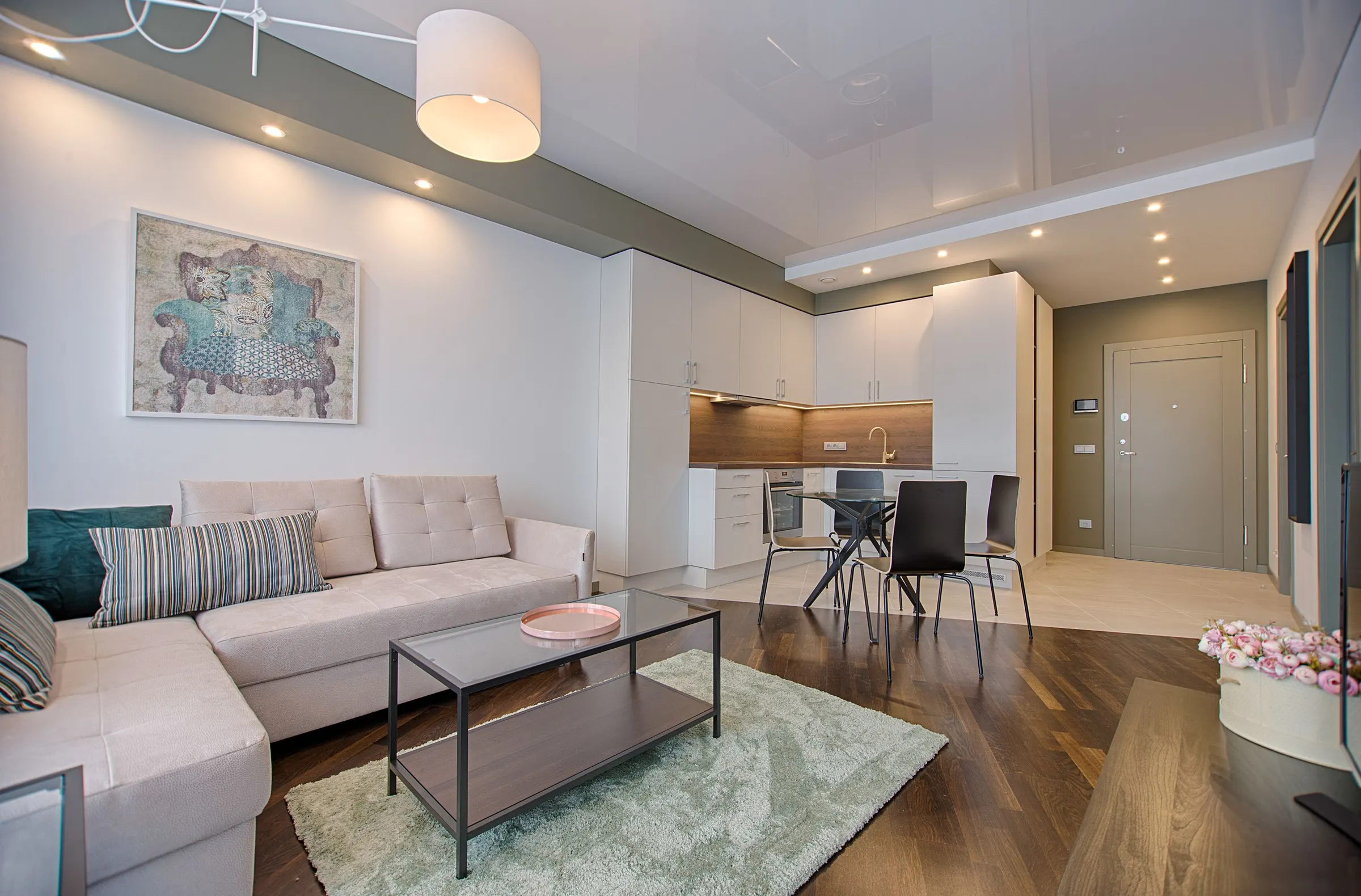 Modern living room with soft white and greige painted walls opening to a white kitchen